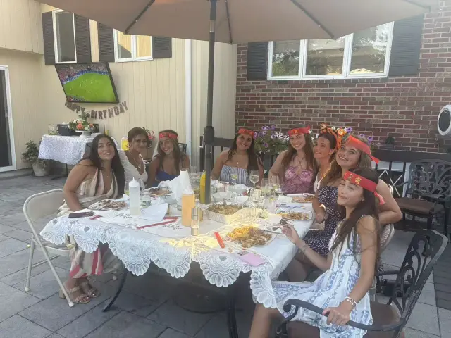 Birthday guests wearing flower crowns at a patio hibachi dinner