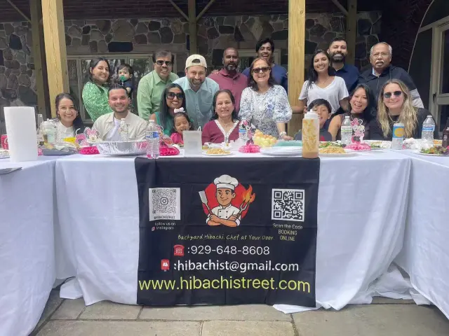 Large family reunion seated at a hibachi dinner table on a stone patio