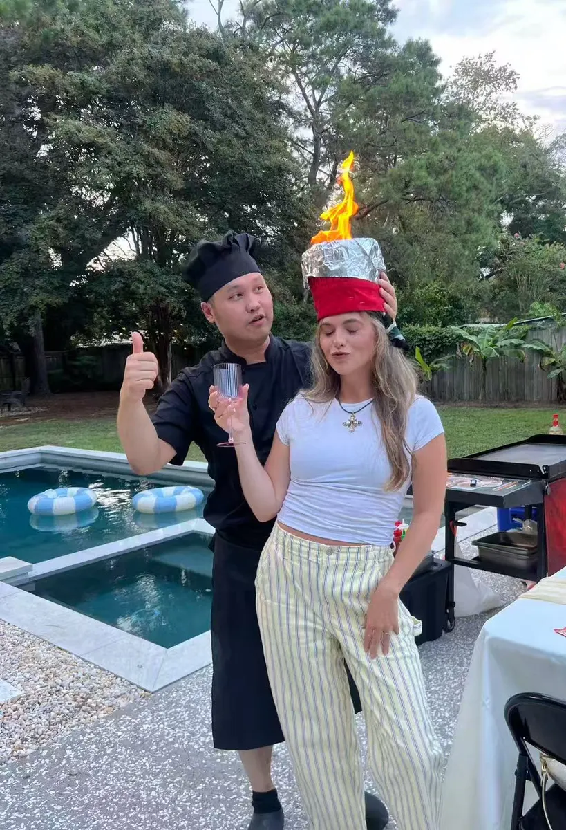 Hibachi Street chef posing with a guest wearing a flaming chef hat by the pool